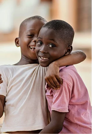 Two joyful boys embrace and smile at the camera, showcasing friendship and happiness.