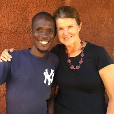 Smiling man and woman posing together against a textured red wall.